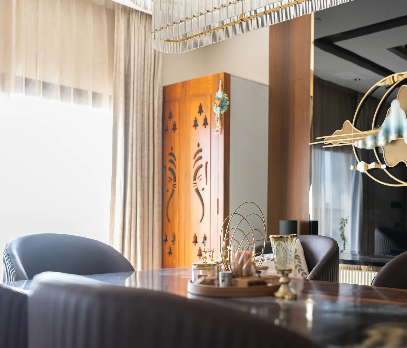 Dining area with carved wooden pooja door and gold ring sculpture — Abhishek's Residence